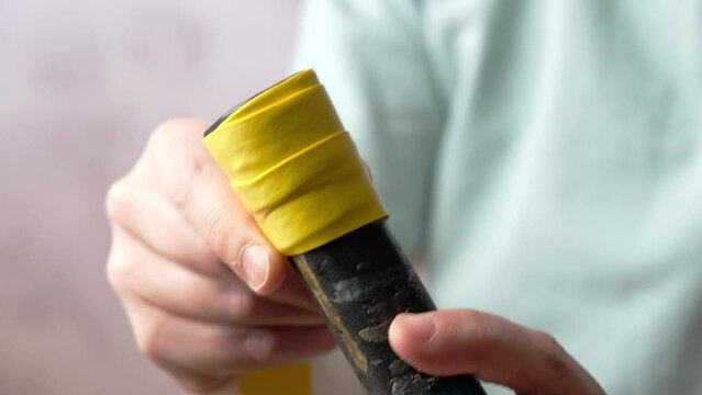 Close-up of the overgrip change on the racket. Woman Pulls the overgrip and wrapped it around the handle of racket.