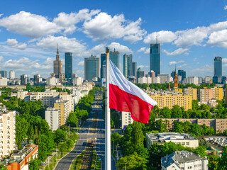 Polish national white and red flag against skyscrapers in Warsaw city center, aerial landscape under clear blue sky