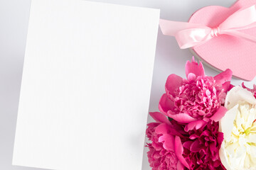 Holiday floral background with peonies. Pink peonies, blank poster for text and  heart-shaped gift on white background. Birthday, Wedding, Mother's Day, Valentine's day, Women's Day.
