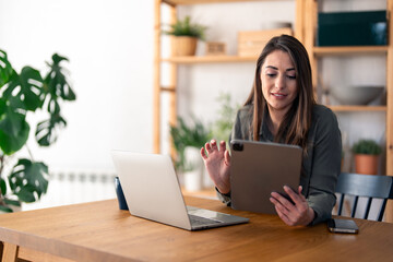 Happy smiling woman entrepreneur holding digital tablet while working in a home office.