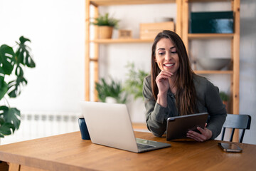 Happy female business professional discussing over video call on laptop while sitting at desk in...
