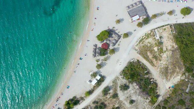 
scenic aerial view of the coastline.  white pier goes into  transparent blue sea. Vacationers on  beach. Makarska. Croatia, Dolmatia 