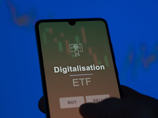 An investor analyzing the digitalisation etf fund on a screen. A phone shows the prices of...