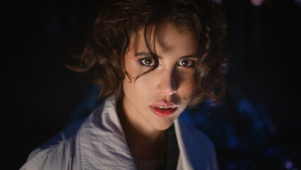 Mysterious woman posing darkness illuminated light closeup. Model at night