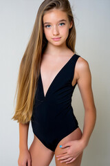 Fototapeta premium Girl in black swimsuit on homogeneous light background