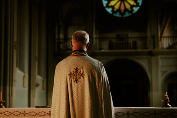 Back view shot of unrecognizable Catholic priest standing at table getting ready for Holy Communion...