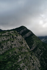 Rocky mountains with steep cliffs and a green forest in late spring. Hills in fog and clouds on a warm summer day. Bar city in Montenegro country. A fascinating landscape.