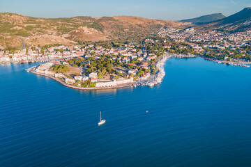 Aerial establishing shot of sail yacht cruising near Foca resort town, Izmir region Turkiye