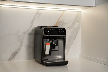 Modern automatic coffee machine on table in kitchen