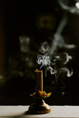Vertical closeup of blown out candle on table with smoke in darkness, copy space