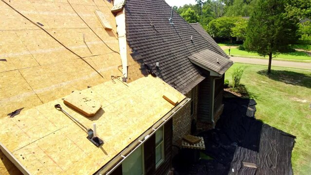 House with new roof being installed, with shingles and exposed deck boards.