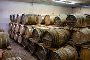 Aging process of cognac spirit in old dark French oak barrels in cellar in distillery house, Cognac...