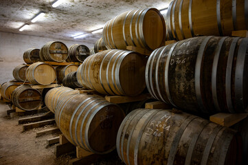 Aging process of cognac spirit in old dark French oak barrels in cellar in distillery house, Cognac...