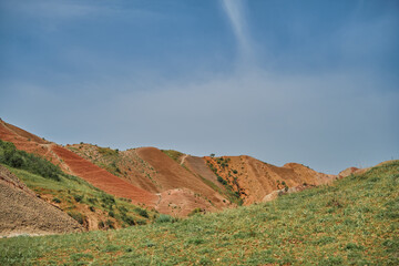 Stunning landscape with colorful hills and lush green fields under blue skies. The vibrant terrain and expansive valley create a breathtaking view and invite you to explore the Georgian wilds