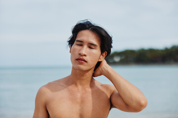 Smiling Asian Man Enjoying Vacation on Tropical Beach: Muscular Torso, Happy and Fit in Swimwear