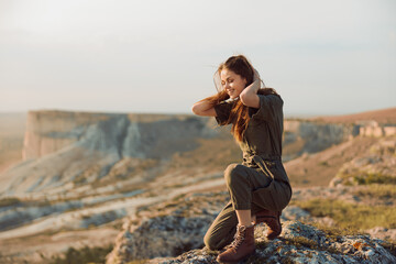 Woman contemplating the beautiful horizon on cliff edge with hands on head in travel adventure...