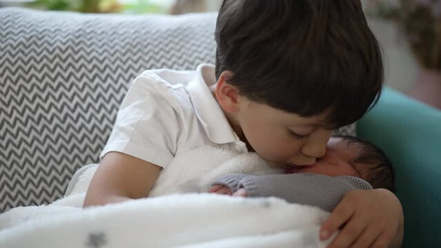 Loving moment as a young boy gently kisses his newborn sibling's forehead, capturing the deep bond and affection between the two brothers, showcasing pure familial love and tenderness