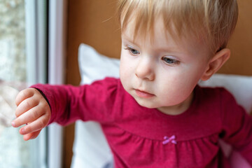 A little girl looks out the window with curiosity and interest.