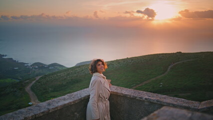 Naklejka premium Smiling woman enjoy sunset overlooking scenic horizon. Stylish traveler relaxing
