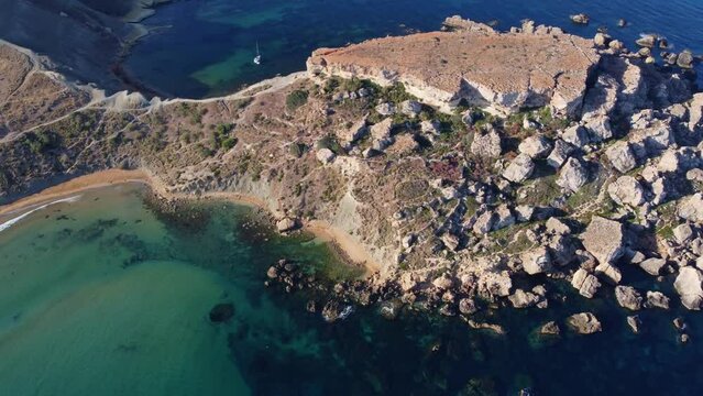 Qarraba Bay flat rock cape Malta, Aeriale stablishing shot in the morning sunlight showing hiking trekking path and two beaches on both side. High quality 4k footage