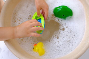 happy child, toddler 3 years old plays with rubber yellow duck for swimming, children's hand...