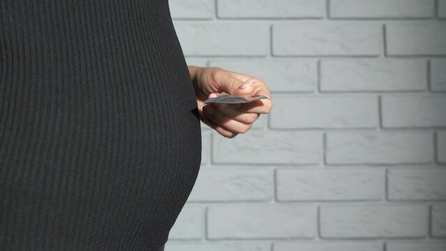 Condom against pregnancy in hands. A view of pregnant female hold condom in her hands. A concept of contraceptives in woman's life.