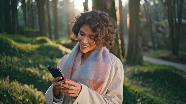 Serene traveler texting mobile phone in calm sunlit forest closeup. Happy woman