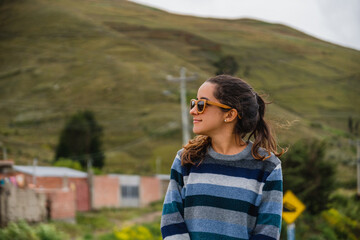 Happy casual dressed woman smiling outdoors, a mountain in the background