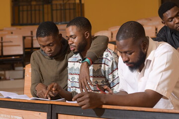 Happy young African university students studying with books in school library