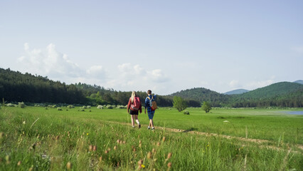 Two young adults, male and female, with backpacks, enjoying time together during a hike on a beautiful sunny spring day.