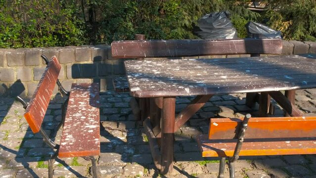 The birds pooped on the bench. View of the table with benches for rest, stained with bird droppings.