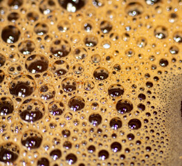 textured foam bubbles with bokeh effect on the surface of hot coffee cup