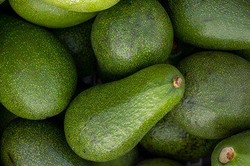 Freshly harvested avocados grouped together in a tight frame, showcasing their vibrant green color and appetizing appearance