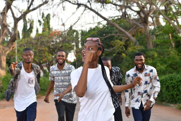 Happy people girls and boys having fun and running outdoors. Smiling students in casual clothes spending time together.