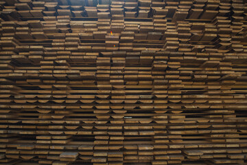 A large stack of lumber boards is neatly stacked at a lumber yard. The boards are arranged in a...