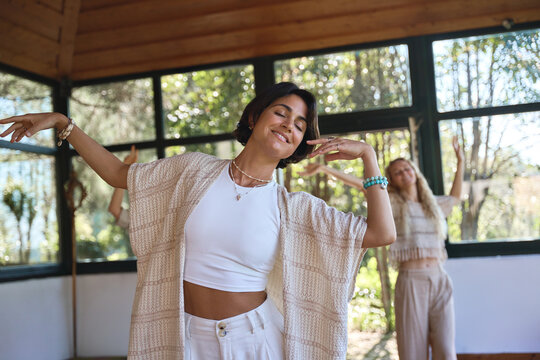 Happy young women community dancing moving together during spiritual practice meditation experience felling energy, peace and love. Dance healing holistic therapy concept.