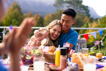 Happy diverse group of friends embracing and having dinner with flags of usa