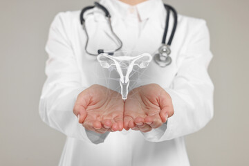 Doctor and illustration of female reproductive system on grey background, closeup