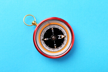 Compass on light blue background, top view. Navigation equipment