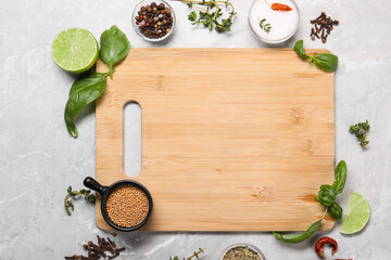 Wooden cutting board surrounded by spices on grey marble table, flat lay. Space for text