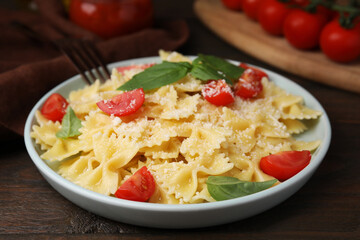 Tasty pasta with tomato, cheese and basil on wooden table, closeup