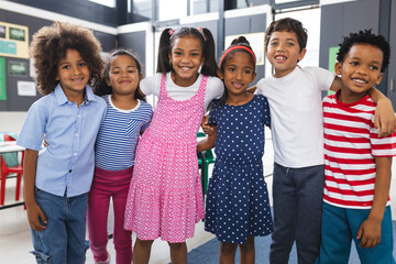 In school, six young students are standing together in classroom, smiling