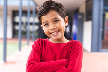 In school, outdoors, biracial young boy standing, smiling at camera