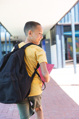 Biracial boy heads to school, backpack in tow