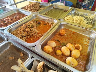 Food stalls share a variety of buffet menus with vegetables, chicken curry sauce, beef, eggs, tofu, tempeh. the waiter prepares the food. Menu in glass display case. Asia and asian food. Pile.