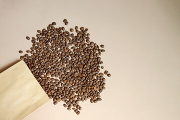 Coffee Beans Spill Out From Packaging With Copy Space Isolated On Beige Background	