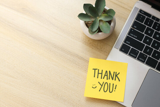 Top View Of Yellow Sticky Note Written Thank You on Laptop With Succulent Over Wooden Background