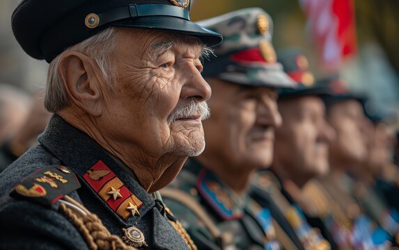 Closeup of elderly veteran in uniform, celebrating with fellow veterans at a commemoration event outdoors.