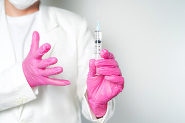 doctor or scientist holding a syringe in pink gloves