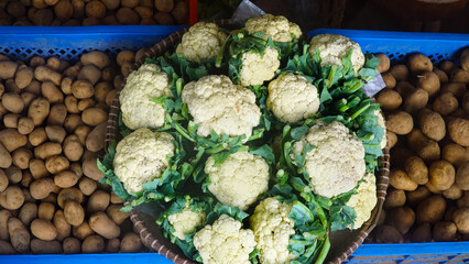 Cauliflower in bamboo basket at traditional market stall. Focus selected. Top view